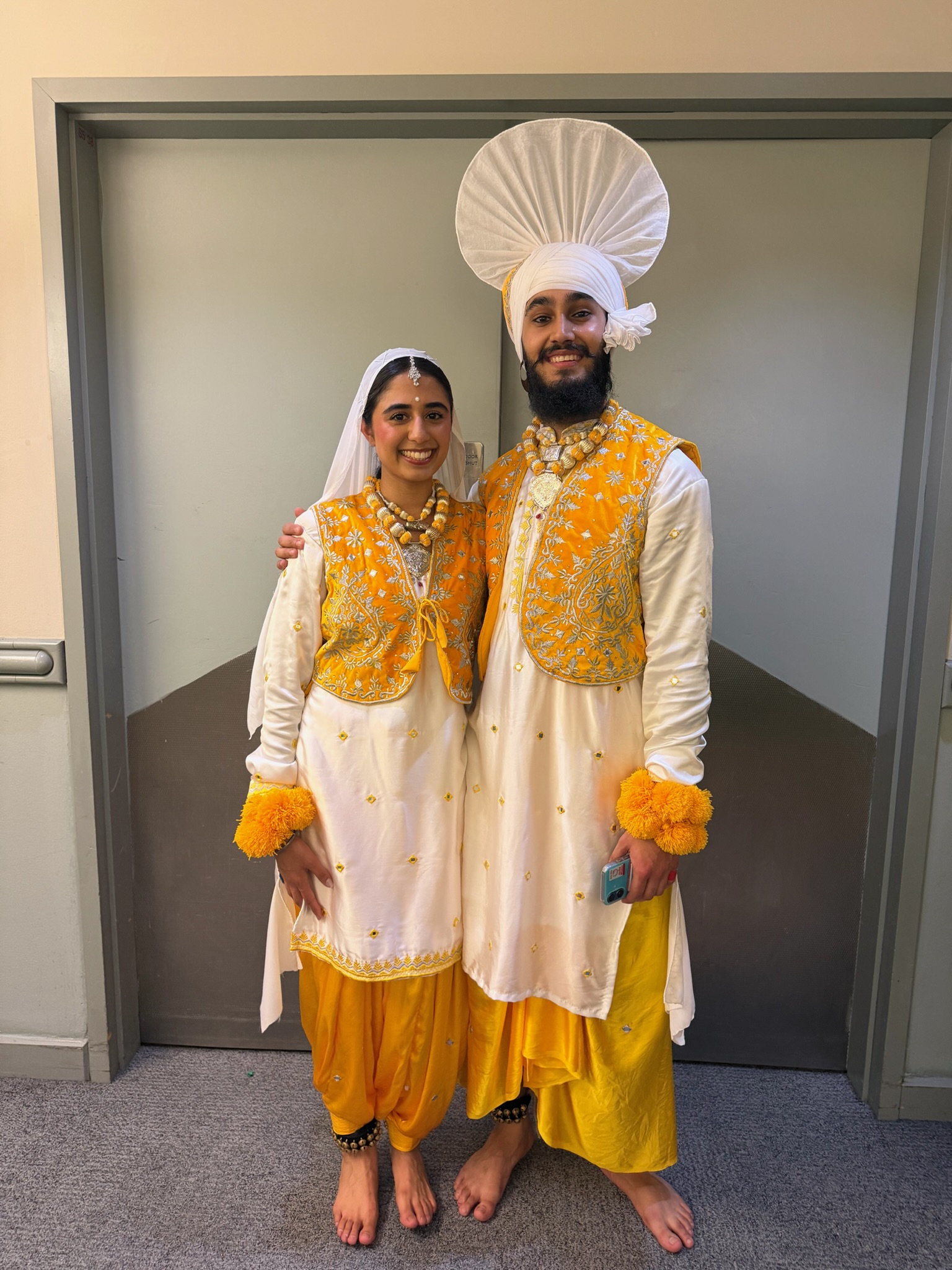 Two LU Bhangra dancers in matching yellow and white costumes